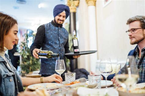 Friends Dining In An Indian Restaurant Waiter Pouring Wine In Glasses