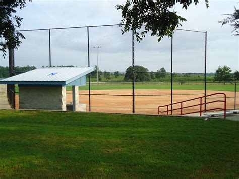 A Baseball Field With A Fenced In Area Next To It And Grass On The Ground