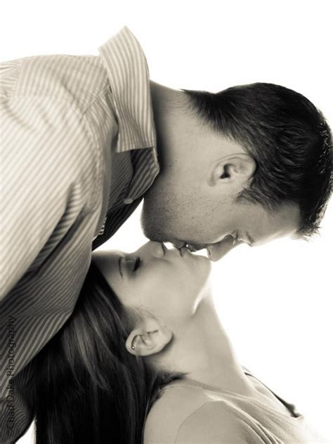 A Man And Woman Kissing Each Other In Black And White