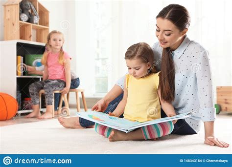 Kindergarten Teacher Reading Book To Child Indoors Learning And