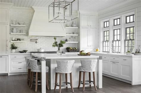 A sturdy cooking center turns a plain barbecue. Polished nickel box lanterns hang from a white shiplap ...