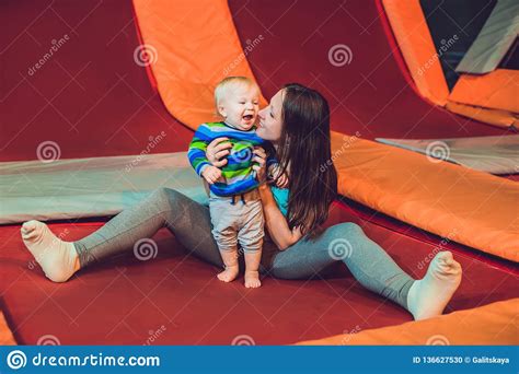 Mother And Her Son Jumping On A Trampoline In Fitness Park And Doing Exersice Indoors Stock