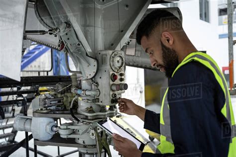 Male Aircraft Maintenance Engineer Examining Engine Of An Aircraft At