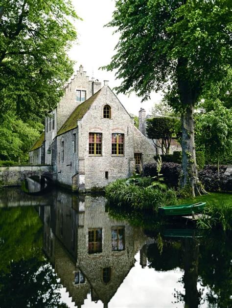 An Old Stone House Is Reflected In The Water