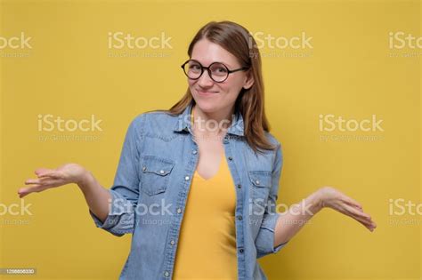 Smiling Focused Young Woman With Glasses Spreading Hands Showing On