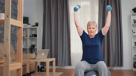 Senior Woman Pumping Shoulder Muscle Using Dumbbells Sitting On Balance