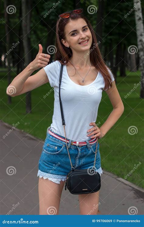 Young Skinny Beautiful Girl Stands In The Park And Smiling Stock Image