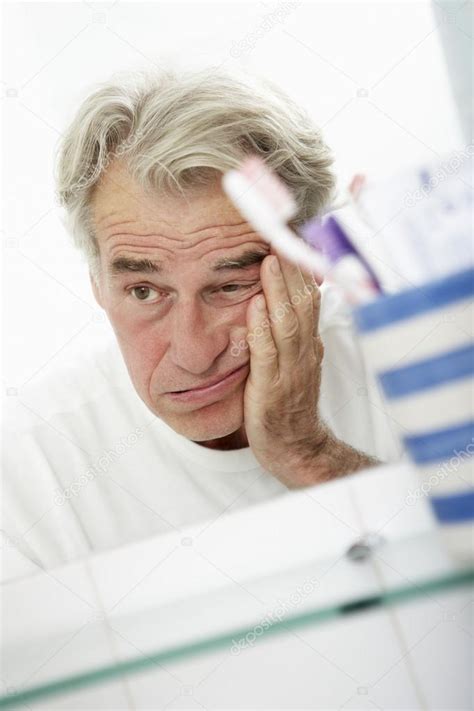 Tired Senior Man Looking At Mirror — Stock Photo © Monkeybusiness