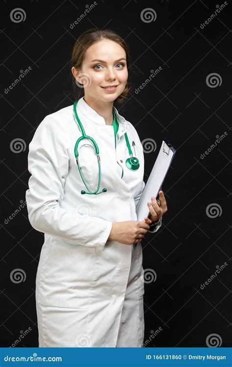 Portrait Of Professional Female Gp Doctor Posing In Doctor`s Smock And Endoscope Against Black