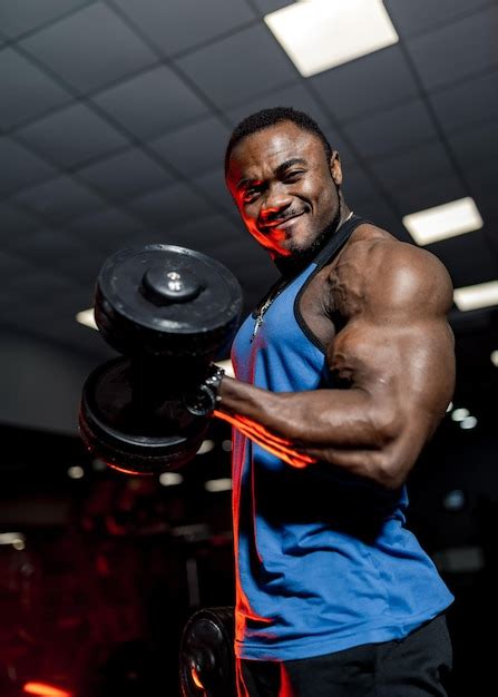 premium photo muscular strong african male athlete lifting heavy dumbbells and pumping biceps