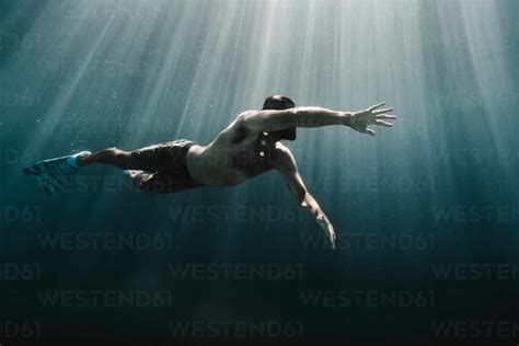 Full Length Of A Man Swimming Underwater In The Ocean Stock Photo
