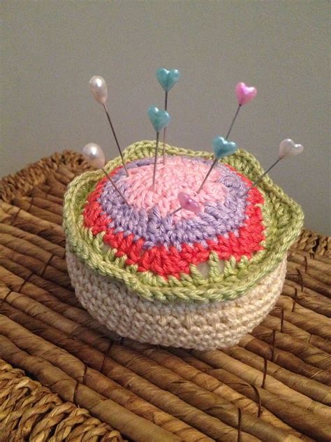 A Crocheted Basket Sitting On Top Of A Wicker Table With Pins In It