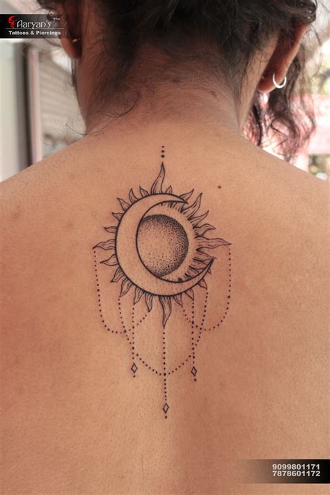the back of a woman's shoulder with a sun and moon tattoo on it
