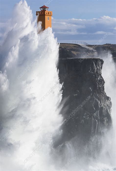 Storm Waves Crashing Against Cliffs Below Lighthouse Stock Image