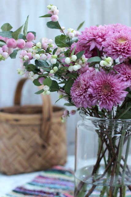A Vase Filled With Pink Flowers Sitting On Top Of A Table Next To A Basket