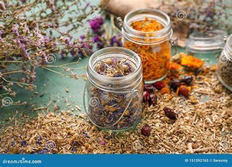 Jars With Aromatic Dried Herbs And Flowers On Color Table Stock Image