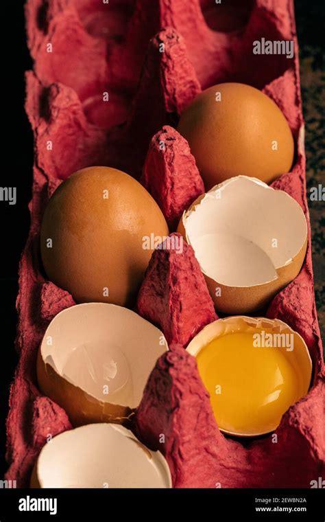 Broken Eggs In A Red Egg Crate One Egg Yolk In The Shell Stock Photo