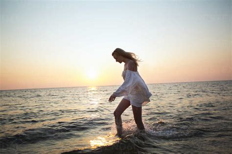 Side View Of Woman Walking In Water At Beach Against Clear Sky Stock Photo