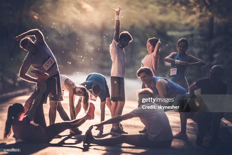 Large Group Of Runners Warming Up On A Road At Sunset Before The