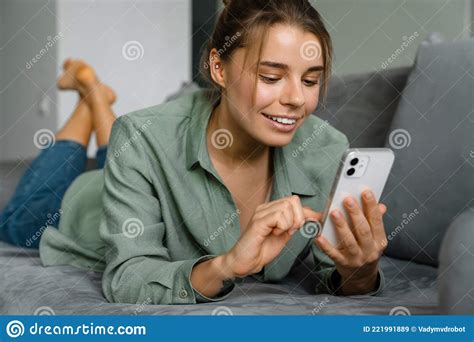 Happy Nice Woman Using Mobile Phone While Lying On Sofa Stock Image
