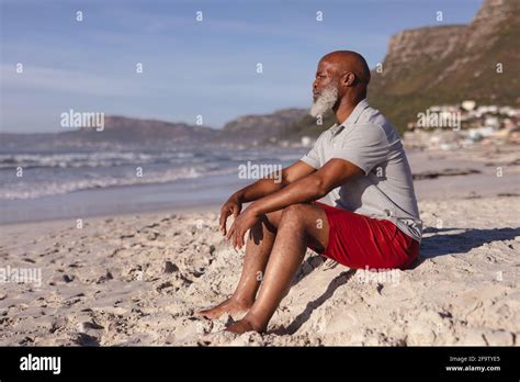 Thoughtful Senior African American Man Sitting Alone On The Beach Stock