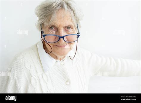 Portrait Of Senior Woman Wearing Eyeglasses On Wall Background Old Woman In White Sweater