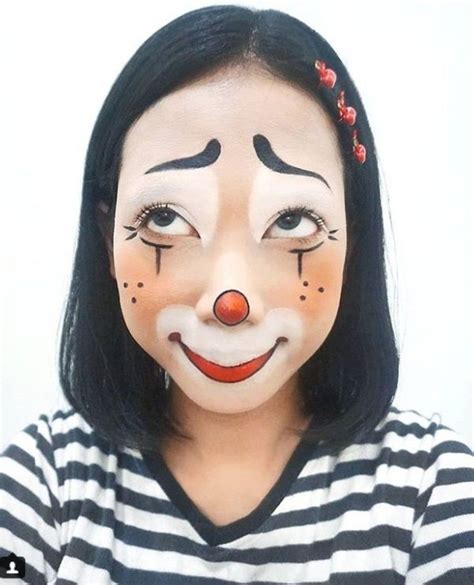 A Woman With Clown Makeup On Her Face Wearing A Black And White Striped Shirt Red Flowers In