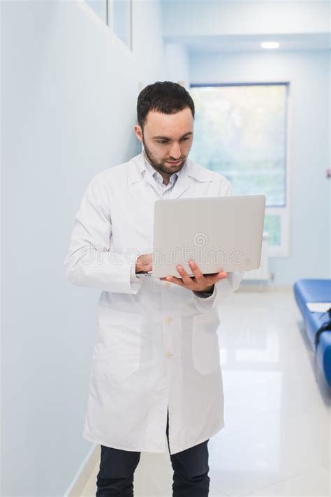 Portrait Of Cheerful Doctor Sitting At The Desk Working On Laptop Stock Image Image Of Coat