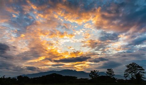 Colorful Cloudy Sunset Sky With Silhouette Of Mountain And Forest Stock