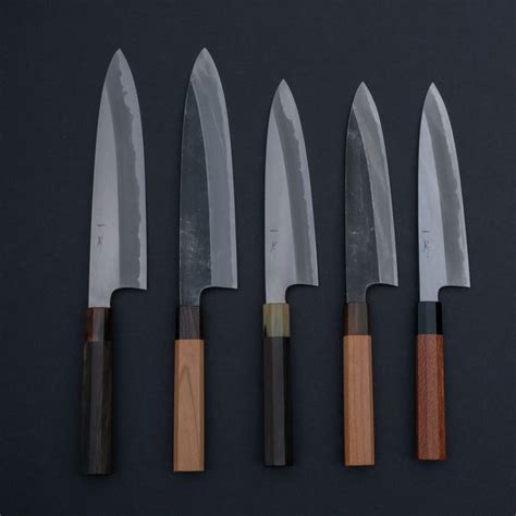 Five Knives Are Lined Up Next To Each Other On A Black Surface With