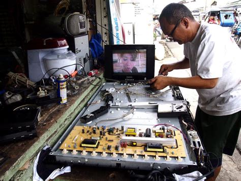 An Electronics Repair Shop Technician Works On A Flat Screen Tv