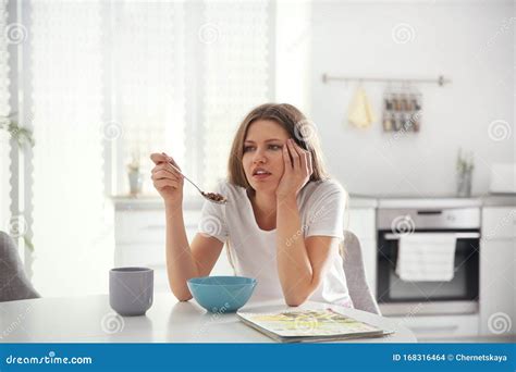 Sleepy Young Woman Eating Breakfast At Home In Morning Stock Photo