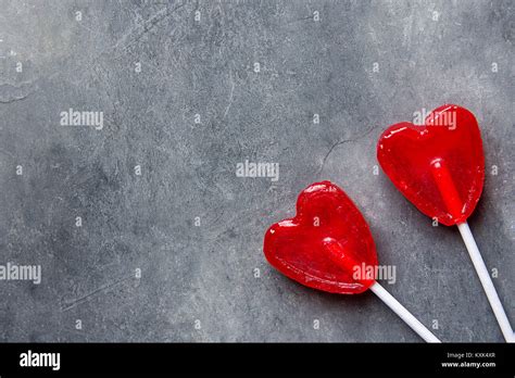 Two Red Heart Shape Candy Lollipops On Sticks On Dark Stone Background