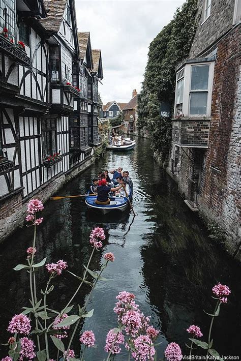 A Group Of People Punting Between Historic Buildings In Canterbury
