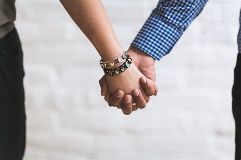 Couple Holding Hands Near White Painted Wall · Free Stock Photo