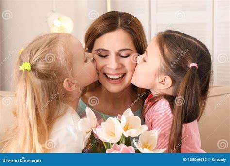 Mother Receiving Flowers From Her Cute Little Daughters At Home Stock