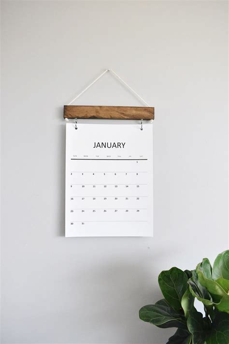 A Calendar Hanging On A Wall Next To A Potted Plant