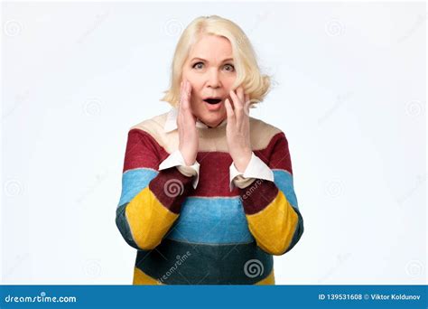 Senior Woman Happy And Surprised Shouts Holds Cheeks By Hand Stock