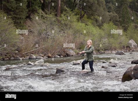 A Young Woman Fly Fishing In A Fast Moving River In The Sierra Nevada