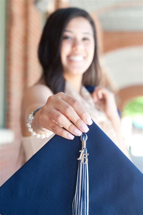 Beautiful High School Graduate Holding Out Graduation Hat Stock Image