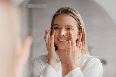 Pretty Lady Making Face Lifting Massage In Bathroom Looking At Mirror And Smiling Using