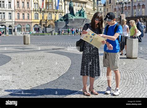 A Woman And Her Son Reading A Map Of Prague With The Jan Hus Sculptures