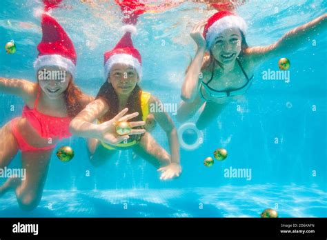 Three Happy Girls Dive And Swim Underwater Wearing Santa Claus Hat In
