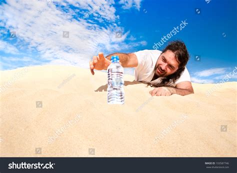 Thirsty Man In The Desert Reaches For A Bottle Of Water Stock Photo