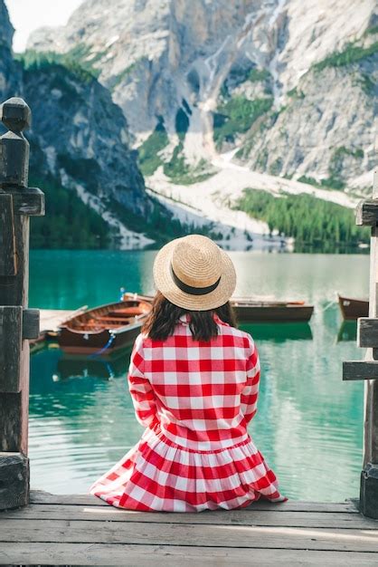 Woman In Red Sundress Sitting On Wooden Stairs Looking At Lake In