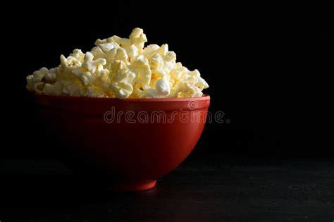Close Side View Of Buttered Popcorn In A Red Bowl Isolated On Black