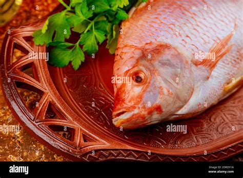 Pink Tilapia Fish With Herbs And Lemon On Tray Close Up Stock Photo