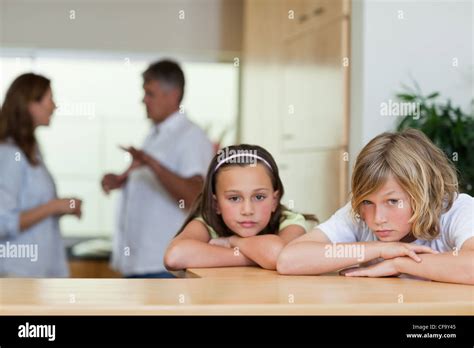 Sad Looking Siblings With Fighting Parents Behind Them Stock Photo Alamy