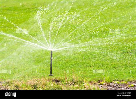 Lawn Sprinkler Spaying Water Over Green Grass Irrigation System Stock