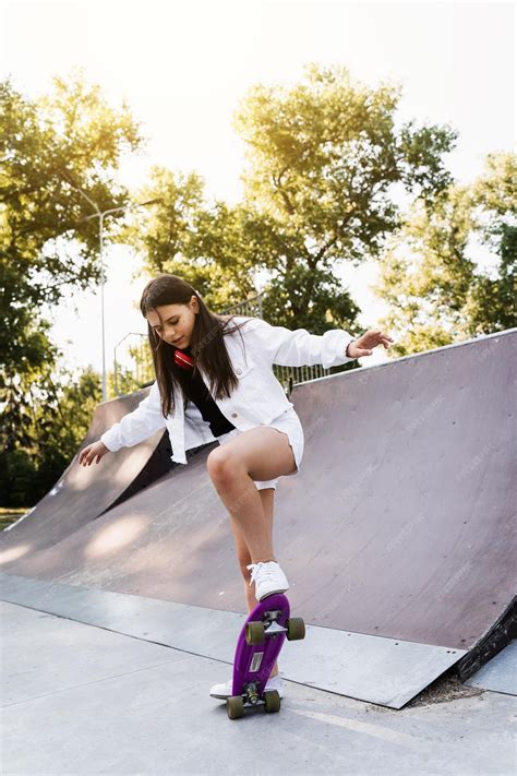 Шокированная девочка перед падением с пенни борда на детской площадке скейт парка на закате